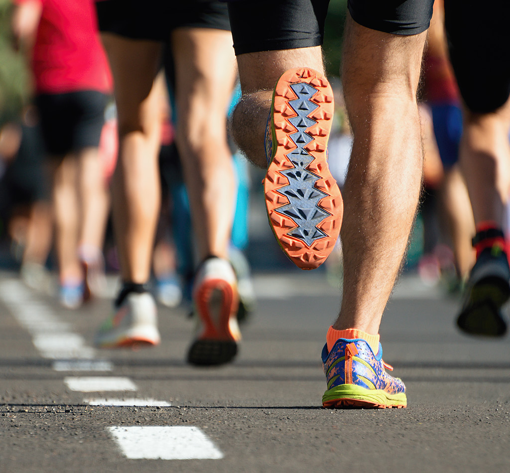 People running a marathon race on a city road, focusing on their running shoes.