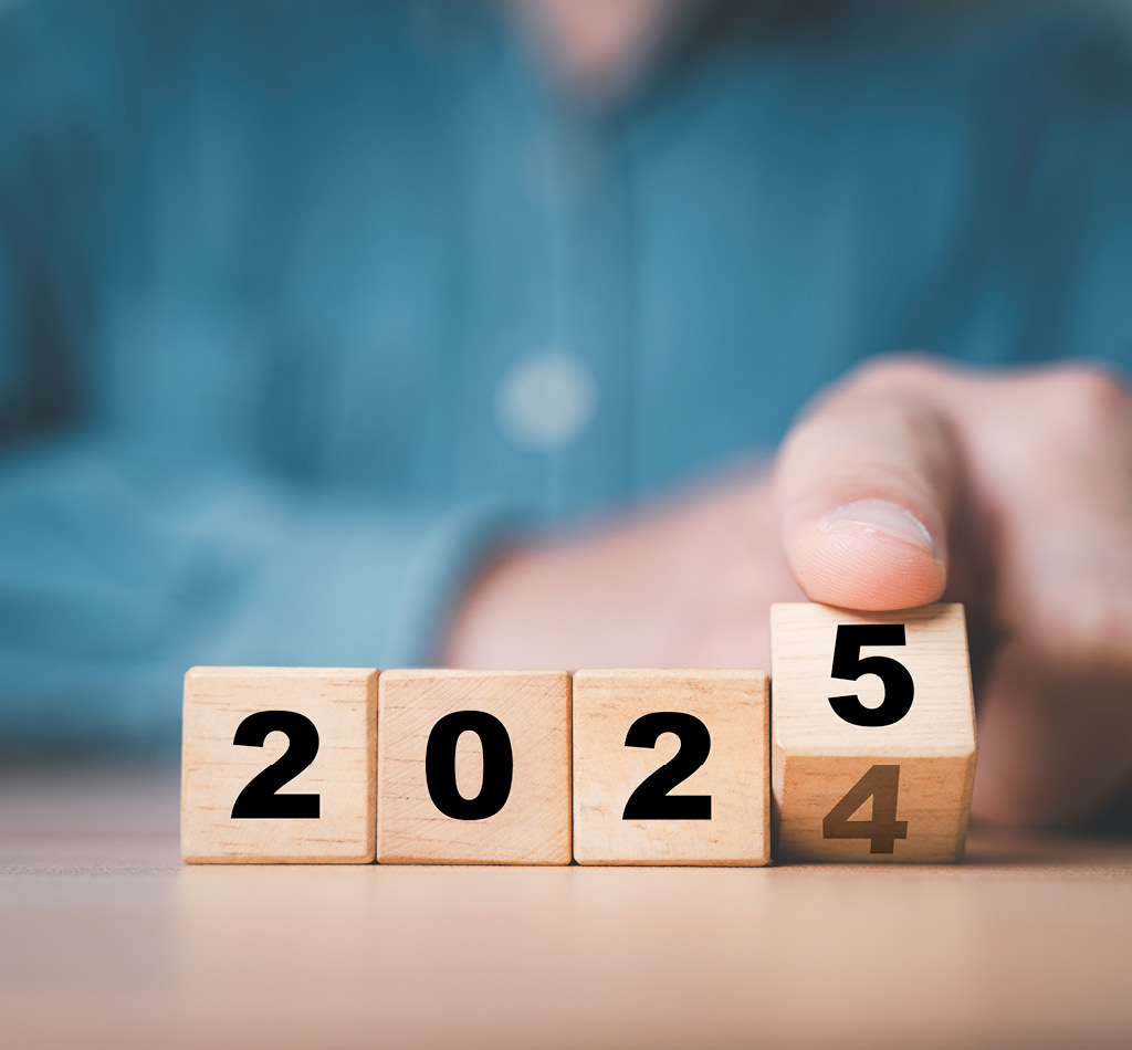 A person flipping a wooden block cube to change 2024 to 2025 in preparation of the new year.