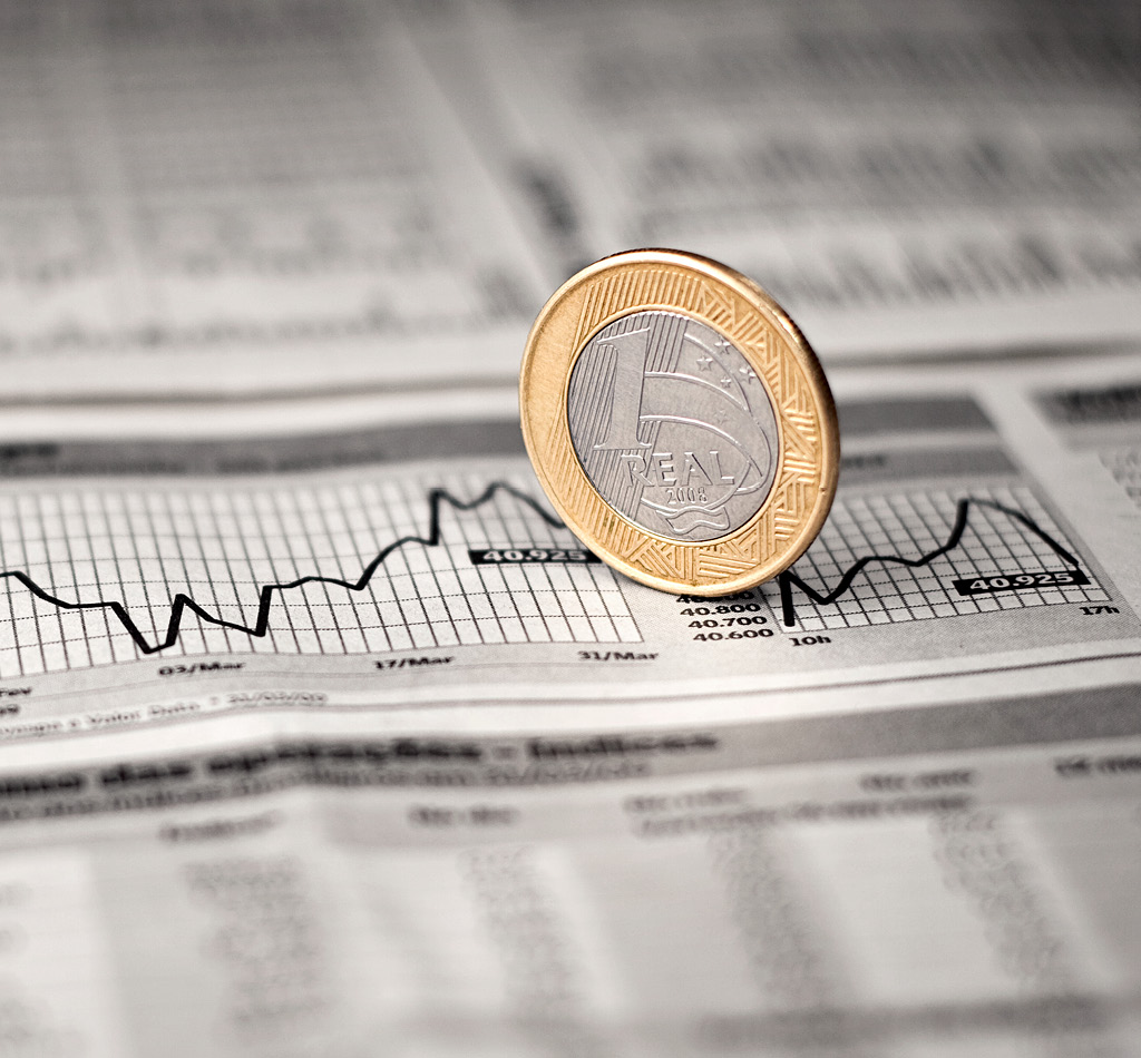 Brazilian economy, a 1 Real coin over a line chart graphic in a newspaper.