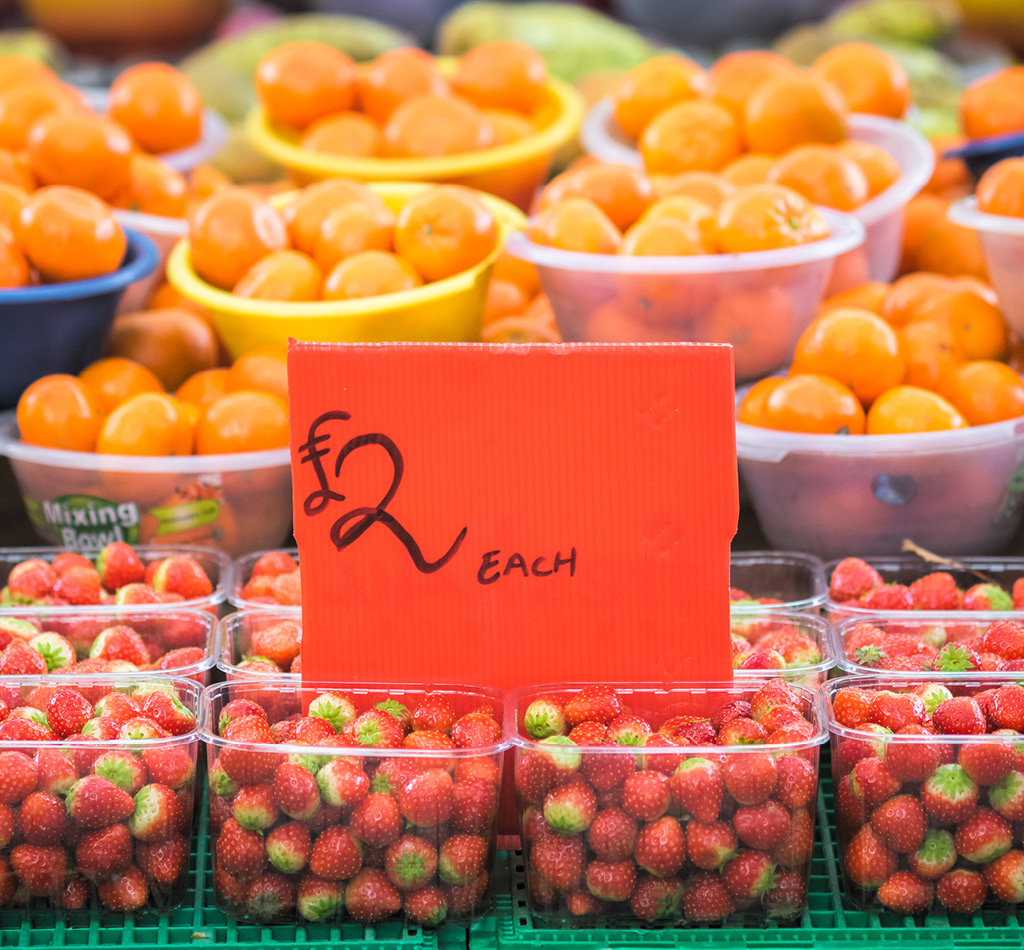 Strawberries and oranges displayed at a fruit stand in a market in London, England.